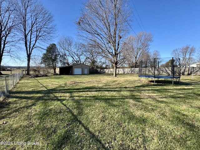 view of yard with a trampoline, a garage, and an outdoor structure