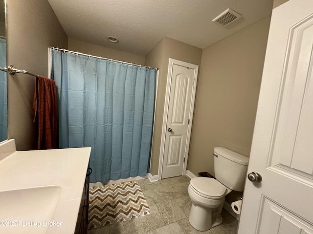 bathroom featuring tile patterned floors, vanity, toilet, and a textured ceiling