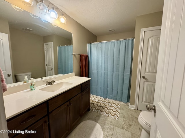 bathroom with vanity, toilet, and a textured ceiling