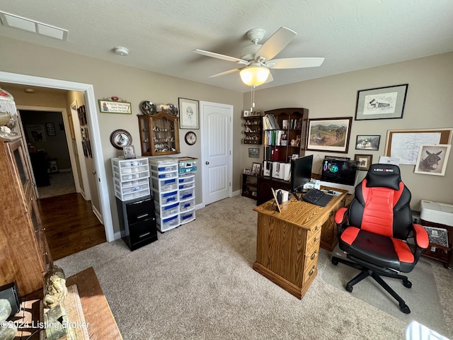 carpeted office space with ceiling fan and a textured ceiling