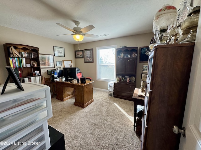 office space featuring a textured ceiling, light colored carpet, and ceiling fan