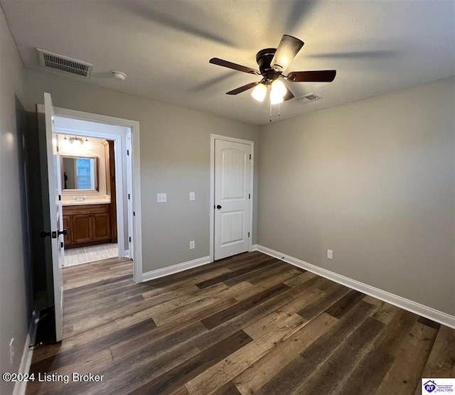 unfurnished bedroom with ceiling fan, ensuite bathroom, and dark wood-type flooring