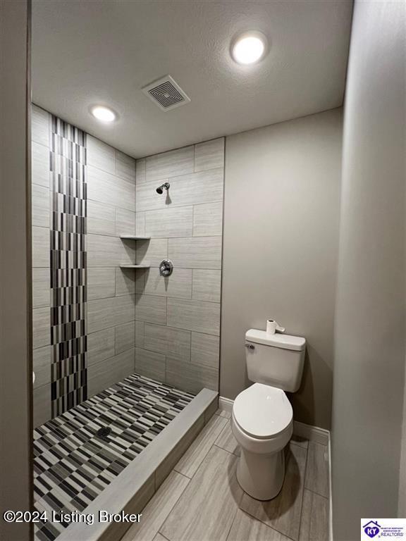 bathroom with toilet and a tile shower