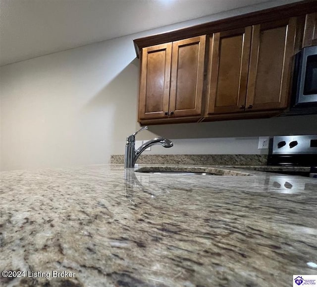 interior details featuring stone counters, sink, and range