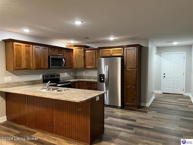 kitchen with sink, stainless steel appliances, a kitchen breakfast bar, dark hardwood / wood-style flooring, and kitchen peninsula