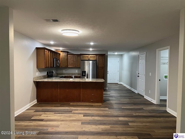 kitchen featuring kitchen peninsula, dark wood-type flooring, and stainless steel appliances