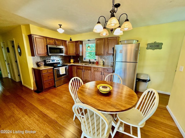 kitchen featuring hardwood / wood-style flooring, decorative light fixtures, appliances with stainless steel finishes, and a notable chandelier