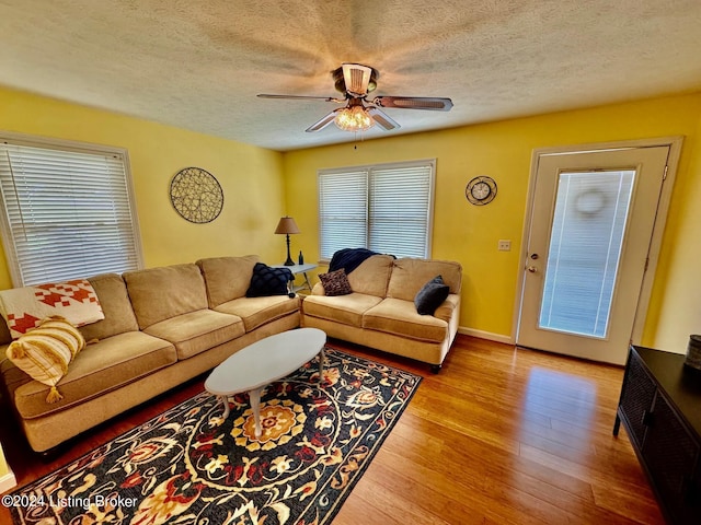 living room featuring a textured ceiling, light hardwood / wood-style flooring, and ceiling fan