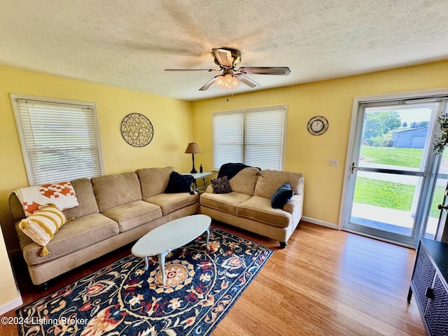 living room featuring a textured ceiling, light wood-type flooring, and ceiling fan