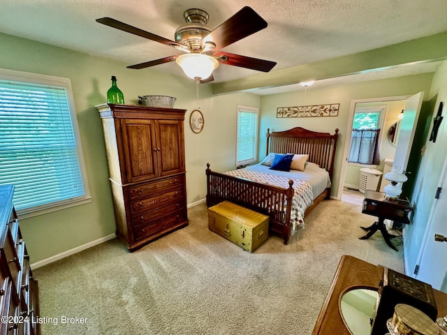 bedroom featuring multiple windows, ceiling fan, light carpet, and a textured ceiling