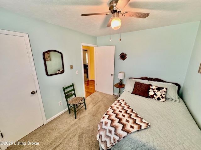 carpeted bedroom with ceiling fan and a textured ceiling