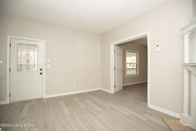 interior space with baseboards, a textured ceiling, and light wood finished floors