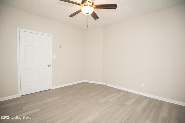 spare room featuring light wood-style floors, a ceiling fan, baseboards, and a textured ceiling