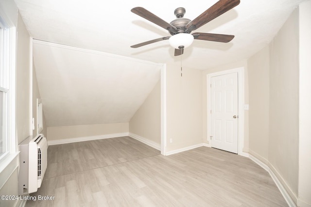 bonus room with a wall unit AC, light wood-style floors, baseboards, and vaulted ceiling