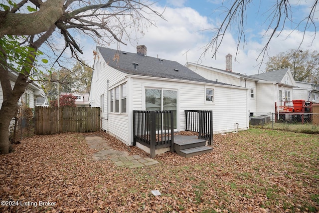 back of house featuring a shingled roof, a chimney, fence private yard, and a wooden deck