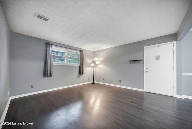 unfurnished room featuring dark hardwood / wood-style flooring and a textured ceiling