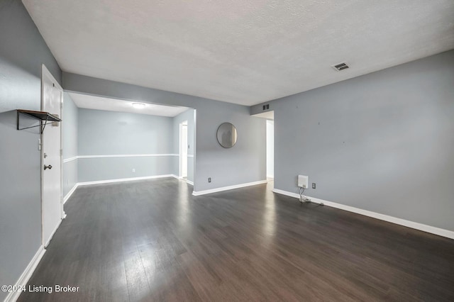 unfurnished room with dark wood-type flooring and a textured ceiling