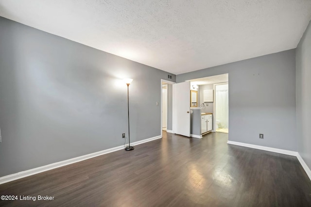 spare room with dark hardwood / wood-style flooring and a textured ceiling