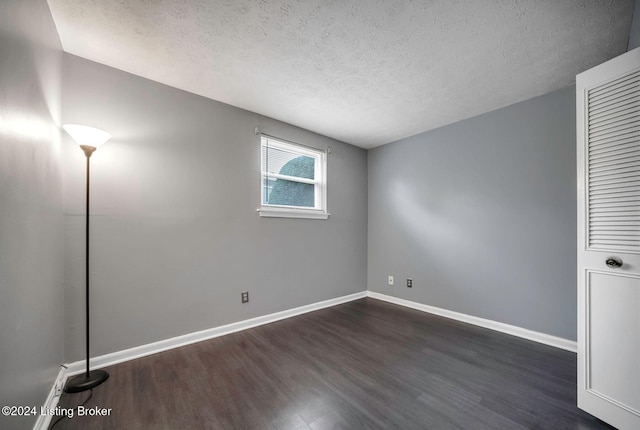 spare room with dark hardwood / wood-style flooring and a textured ceiling