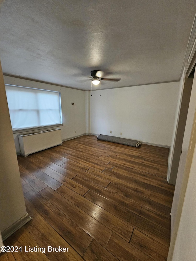 empty room featuring ceiling fan, dark wood-type flooring, and a textured ceiling