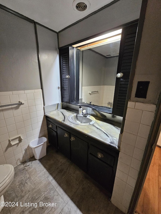 bathroom with tile patterned floors, vanity, toilet, and tile walls