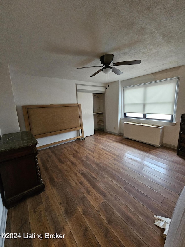 unfurnished bedroom featuring ceiling fan, a closet, dark wood-type flooring, and a textured ceiling