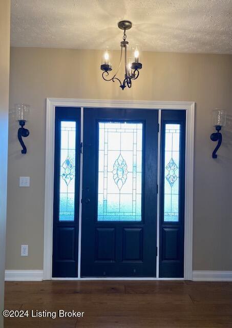 entryway featuring hardwood / wood-style floors, a textured ceiling, and a notable chandelier