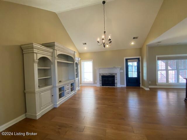 unfurnished living room featuring a wealth of natural light, a fireplace, high vaulted ceiling, and dark wood-type flooring