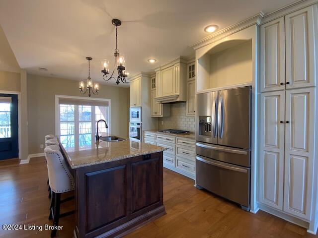 kitchen featuring sink, dark wood-type flooring, light stone counters, a kitchen island with sink, and appliances with stainless steel finishes