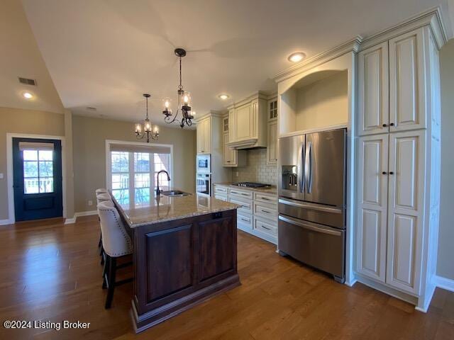 kitchen featuring light stone counters, stainless steel appliances, a kitchen island with sink, sink, and dark hardwood / wood-style floors