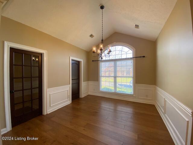 unfurnished dining area featuring a chandelier, dark wood-type flooring, and lofted ceiling