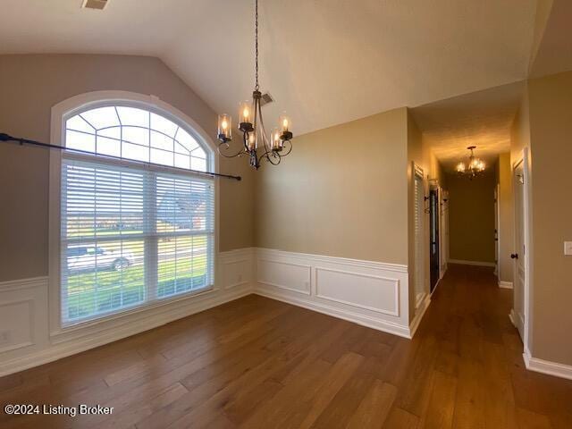 unfurnished dining area featuring a notable chandelier, dark hardwood / wood-style floors, and vaulted ceiling