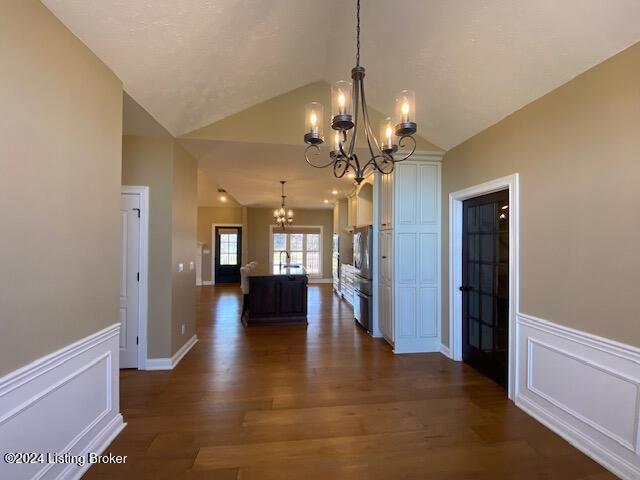 kitchen with dark hardwood / wood-style flooring, a chandelier, lofted ceiling, decorative light fixtures, and a kitchen island