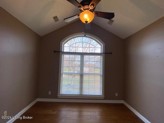 empty room with ceiling fan, dark hardwood / wood-style flooring, and vaulted ceiling