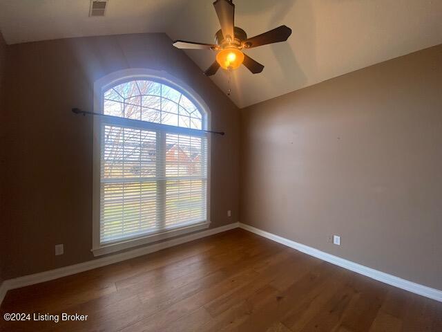 empty room featuring ceiling fan, dark wood-type flooring, and vaulted ceiling