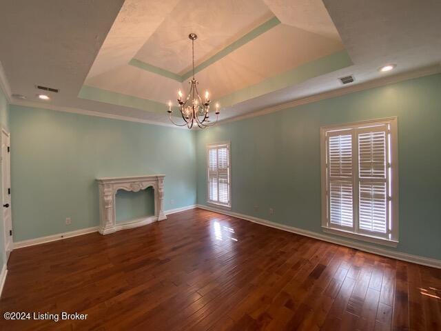 unfurnished living room featuring a notable chandelier, dark hardwood / wood-style floors, ornamental molding, and a tray ceiling