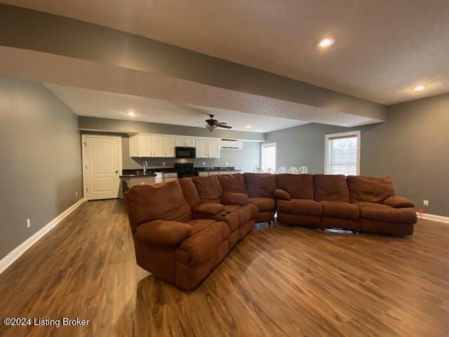 living room featuring hardwood / wood-style floors, ceiling fan, and an AC wall unit