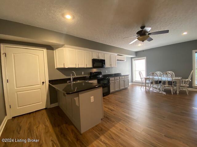 kitchen with black appliances, kitchen peninsula, a textured ceiling, dark hardwood / wood-style flooring, and white cabinetry