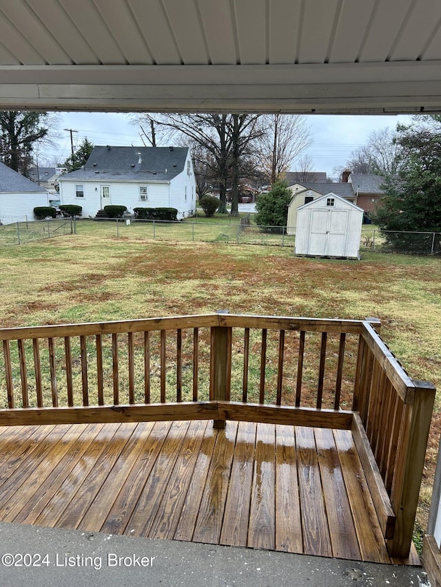 wooden terrace featuring a lawn and a storage shed