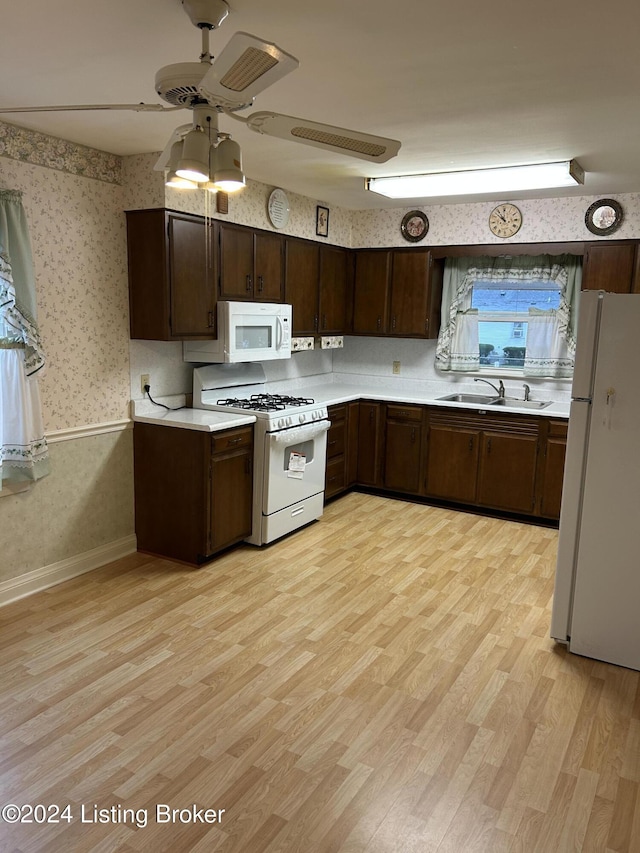 kitchen with dark brown cabinets, white appliances, light hardwood / wood-style flooring, and sink