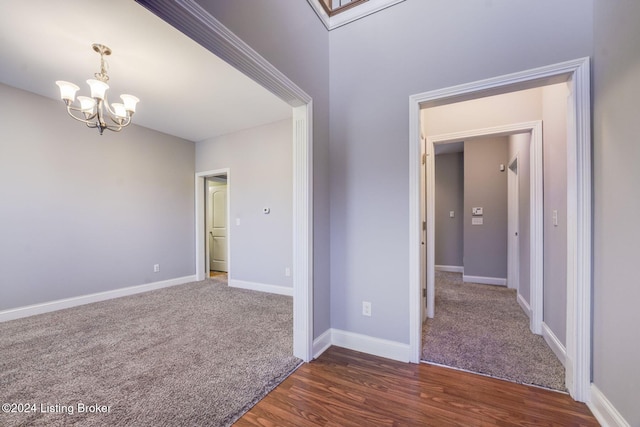 unfurnished room with dark wood-type flooring and a chandelier