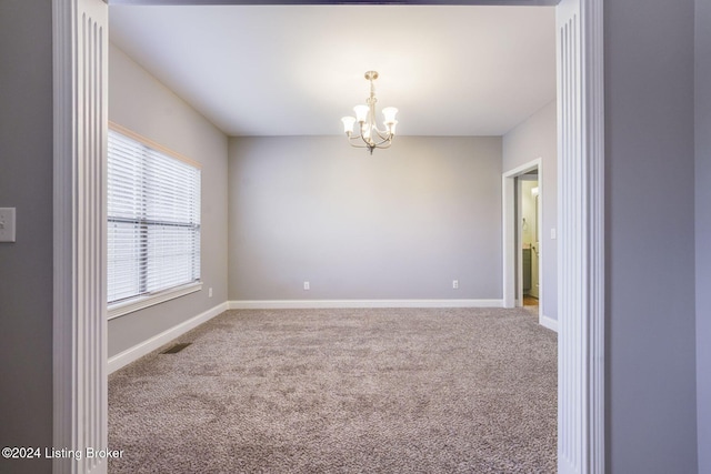 carpeted empty room featuring a chandelier