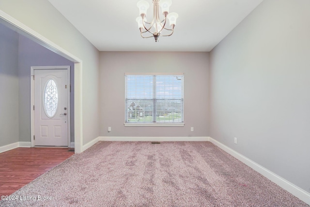 carpeted foyer entrance with a notable chandelier