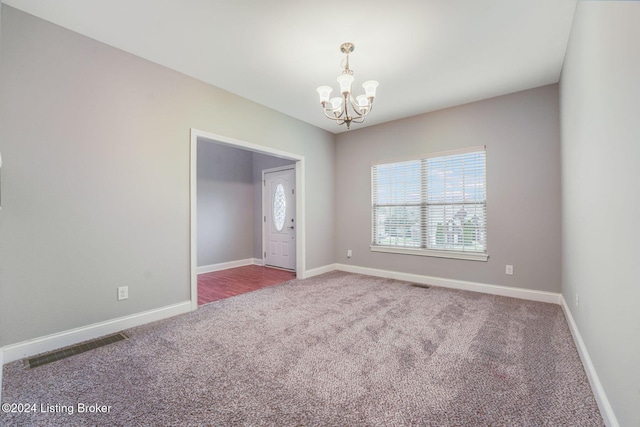 unfurnished room featuring carpet and a notable chandelier