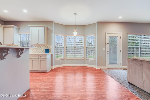 kitchen with white cabinets, decorative backsplash, and a healthy amount of sunlight