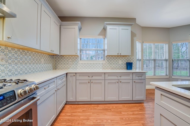 kitchen with gas stove, light wood-type flooring, extractor fan, and tasteful backsplash