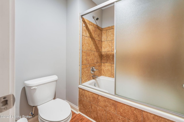 bathroom featuring toilet and bath / shower combo with glass door