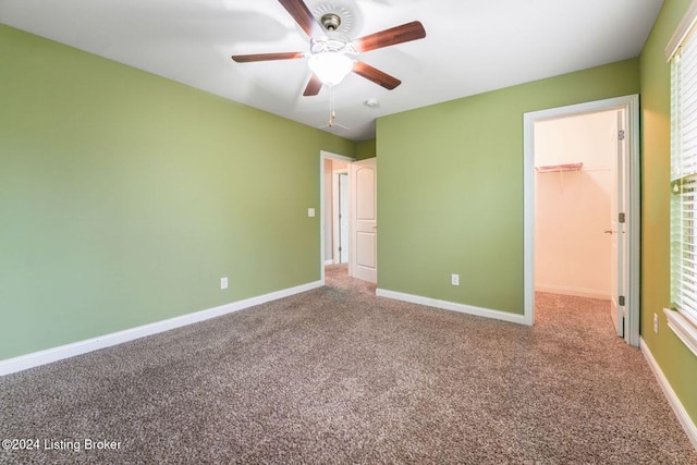 unfurnished bedroom with carpet flooring, ceiling fan, a closet, and a spacious closet