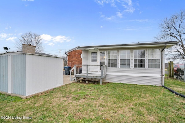 back of property featuring a storage unit and a lawn