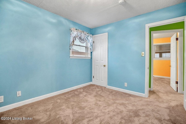 spare room with light colored carpet and a textured ceiling